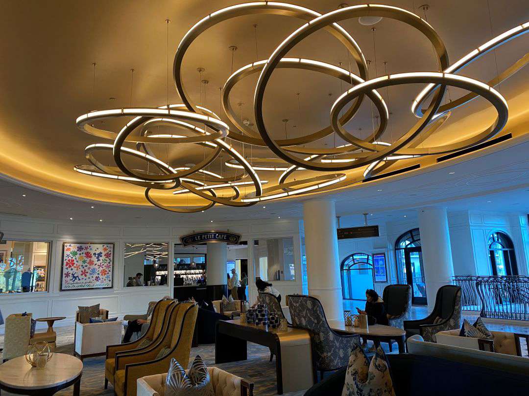 Lobby of a hotel with lots of seats and a chandelier hanging from the ceiling