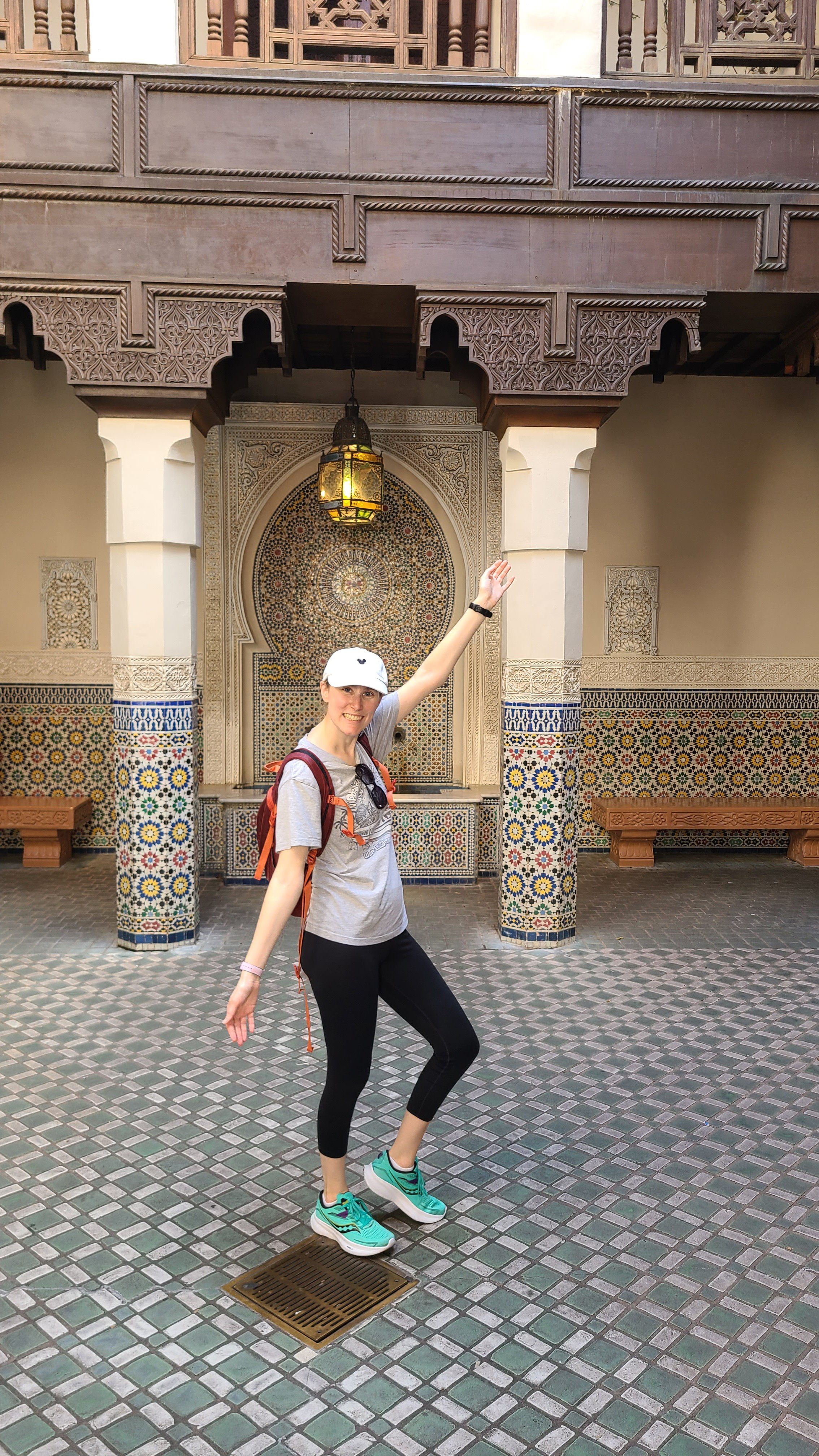 A picture of the blog&rsquo;s author standing inside of the Moroccan pavilion at EPCOT. She is wearing comfortable leggings, t-shirt, and has a baseball cap and sunglasses on. She is also wearing a backpack. 