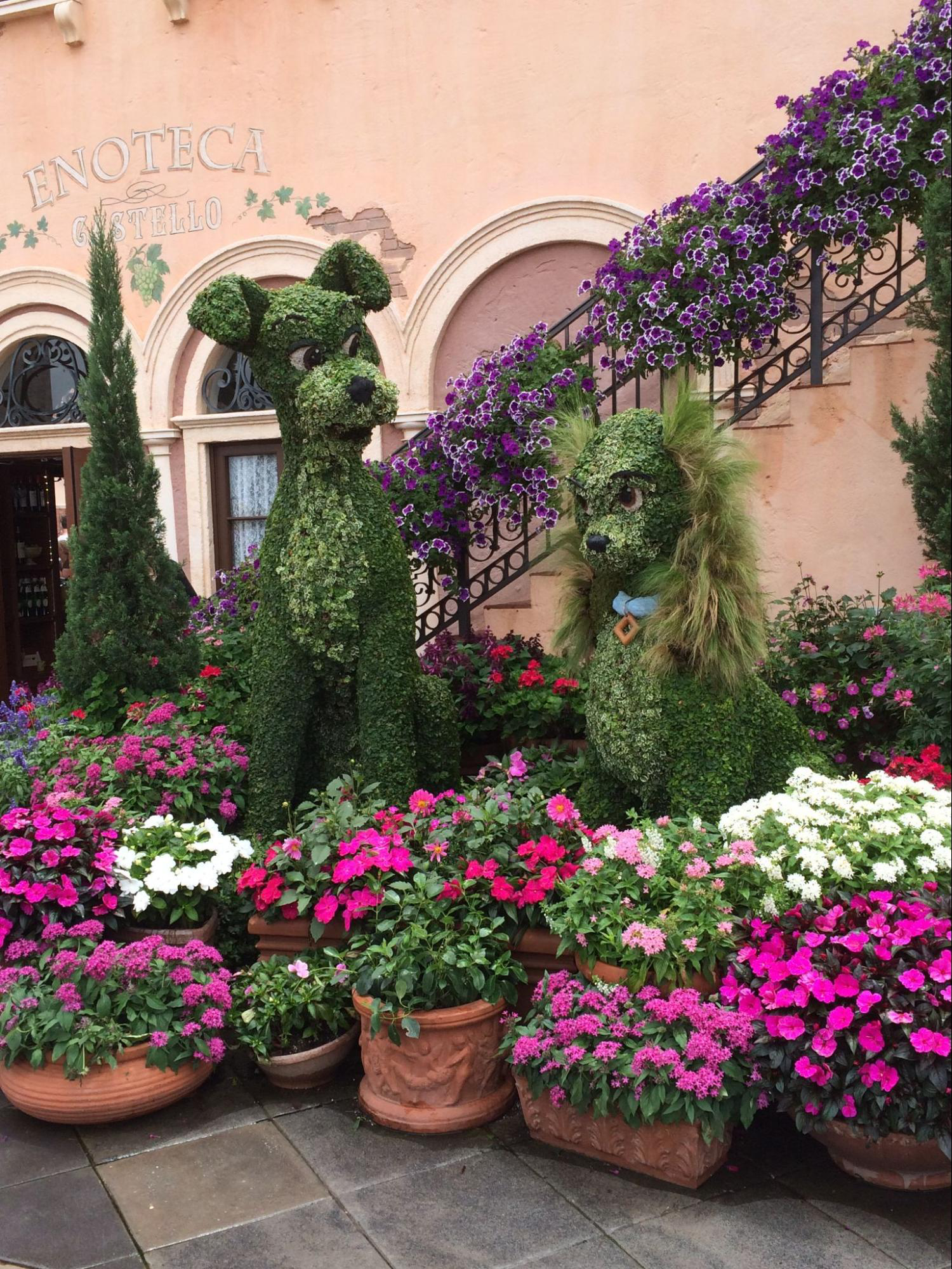 A photo of lady and the tramp topiaries with an Italian backdrop